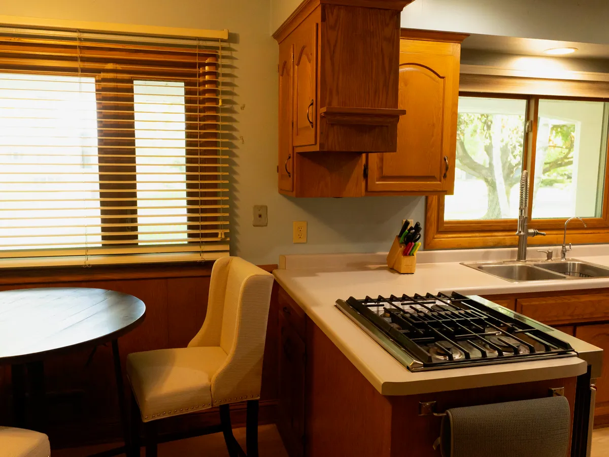 Old oak kitchen with a gas cooktop peninsula and dated cabinets before Powerbuilt Construction remodeled it