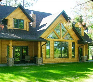 Custom log home with a prow-front window wall, built by Powerbuilt Construction